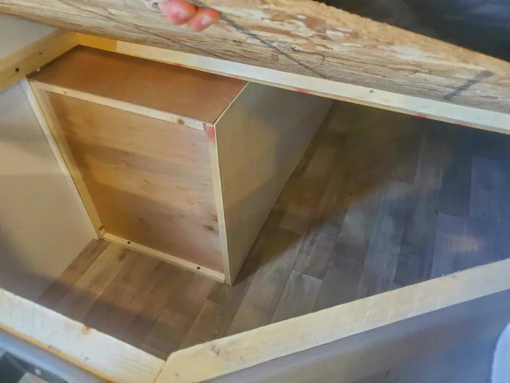 Discover practical RV rental storage! This image shows a hand lifting a wooden hatch to reveal a built-in compartment with a partition.. Keystone 250BH 2022