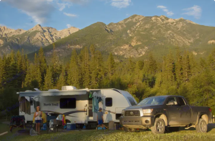 Family camping with an RV rental & truck amidst a majestic mountain and forest backdrop. Outdoor adventure begins!. Heartland RVs North Trail 2013