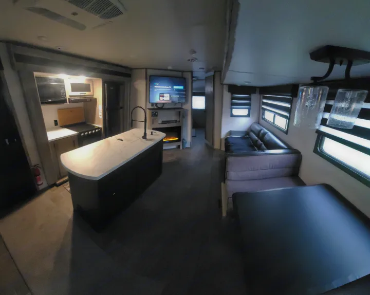 RV rental: Modern interior showcases a kitchen island, living area with TV/fireplace, and dining booth. Your comfy home on wheels.. Forest River Cherokee Alpha Wolf 2021