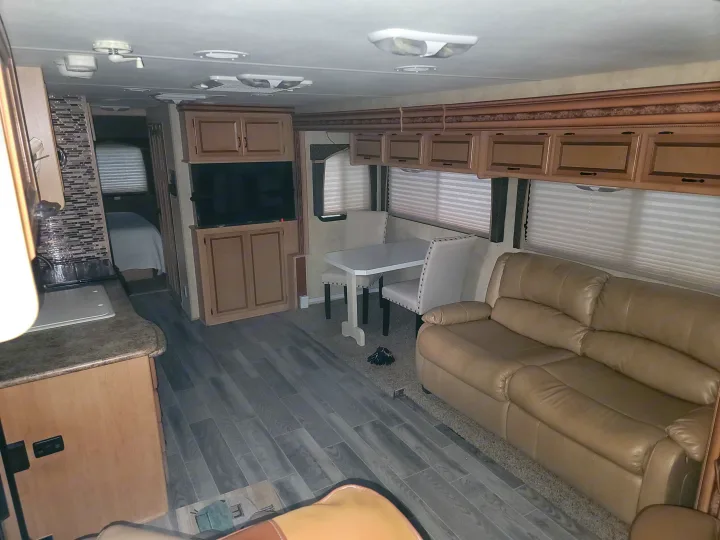 Modern RV rental interior featuring a living area with leather seating, dining booth, and kitchen, designed for comfortable travel.. Thor Hurricane 2012