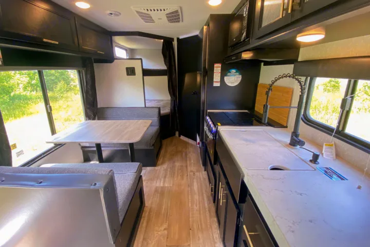 Spacious RV rental interior featuring a full kitchen, comfortable dining area, and rear bunk beds, ideal for travel.. Forest River Cherokee Greywolf 2022