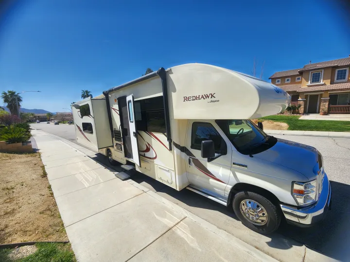 Spacious Jayco Redhawk RV rental parked on a sunny residential street with slide-outs extended.. Jayco Redhawk 2016