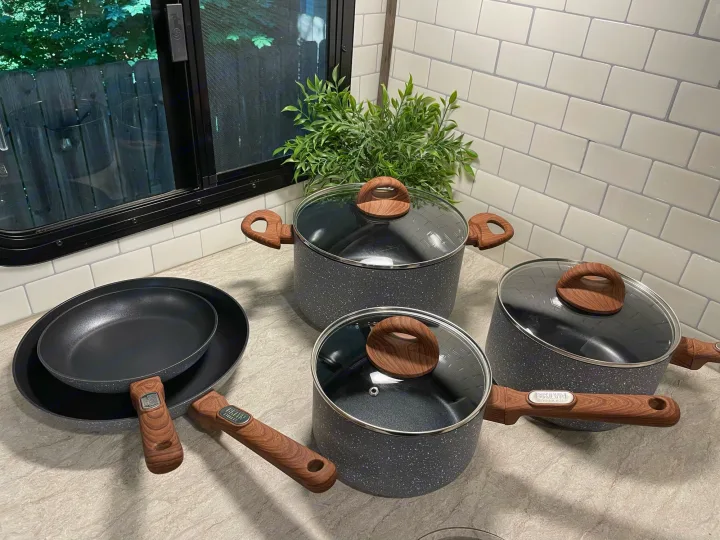 Modern cookware set in an RV rental kitchen. Grey speckled pots & pans with wood handles, ready for travel meals.. Cruiser RV MPG Ultra Lite 2019