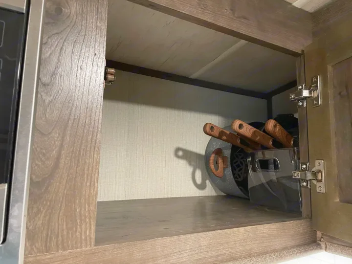 RV rental kitchen cabinet open, revealing nesting pots & pans stored efficiently. A practical space for cooking essentials.. Cruiser RV MPG Ultra Lite 2019