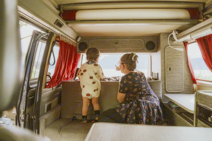 Exploring in an RV rental. An adult points to the scenic view for a child from inside the camper.. Volkswagen Vanagon 1991