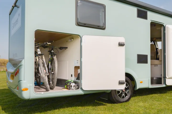 Light green RV rental with open rear storage revealing two mountain bikes & helmets, ideal for outdoor adventures.. GlamperRV DBL 2026