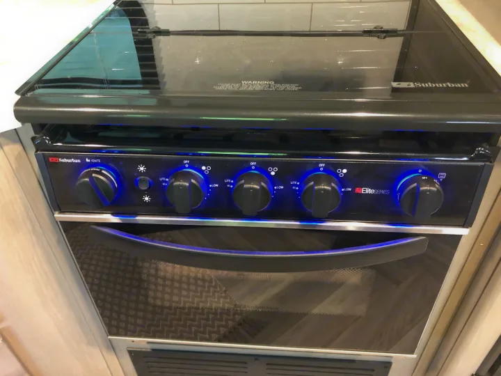 Modern RV rental kitchen features a Suburban stove and oven with blue illuminated knobs.. Cruiser Rv Corp Shadow Cruiser 2021