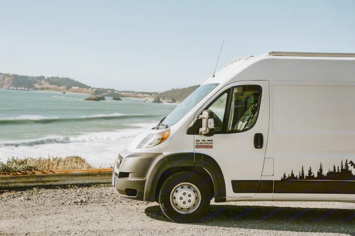 White Ram ProMaster camper van parked on a scenic coastal road with ocean waves. Ideal for an RV rental adventure.. Dodge Ram Promaster 2500 2019