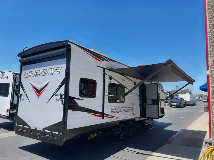 A SHOCKWAVE toy hauler RV rental, with an extended awning, awaits adventure. Ideal for outdoor recreation.. Forest River Shockwave 2022