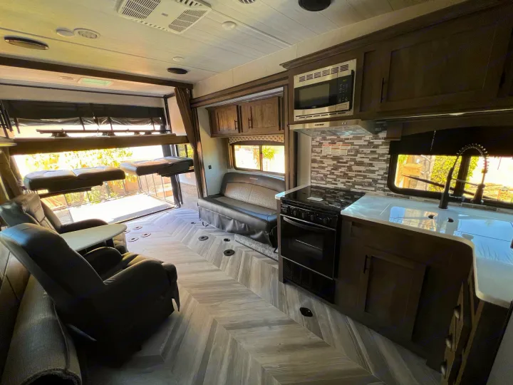 Modern RV rental interior: full kitchen, recliners, and rear ramp access with convertible bunks.. Forest River Shockwave 2022