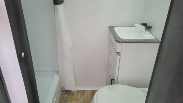 Compact RV rental bathroom with a white shower/tub combo, vanity sink, and toilet.. Keystone Hideout 2022