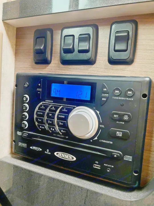 RV rental control panel: a Jensen AWM968 media player with radio, DVD, USB, Bluetooth, and digital clock display.. Itasca Navion 2015
