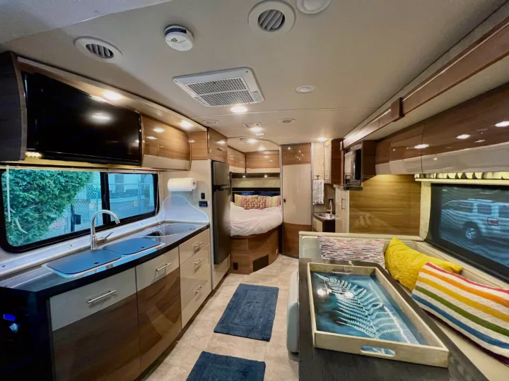 Modern RV rental interior featuring a kitchen, dining area, and comfortable bedroom. Your next road trip awaits in this motorhome!. Itasca Navion 2015