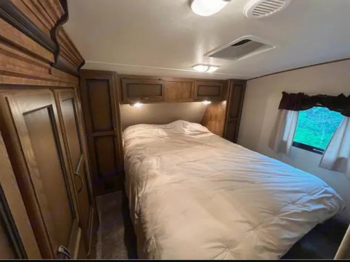 Cozy RV rental bedroom with a comfortable bed, built-in storage, and natural light from windows.. Crossroads RV Rezerve 2016
