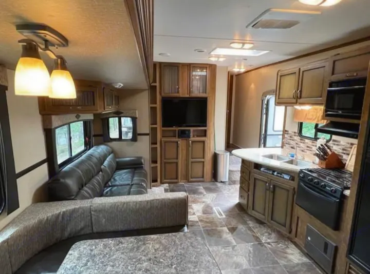 Explore this RV rental's inviting interior: leather sofa, dinette, TV, and full kitchen, ready for your next adventure.. Crossroads RV Rezerve 2016