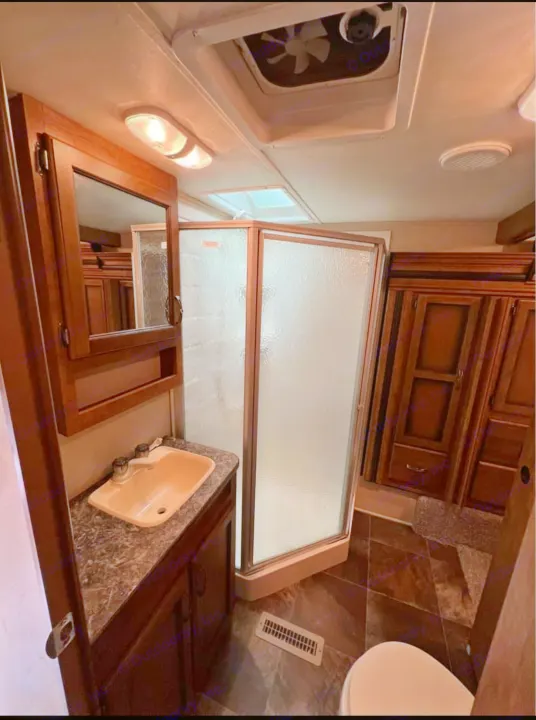 Spacious RV rental bathroom with wood vanity, sink, enclosed shower, toilet, and ceiling vent/skylight.. Crossroads RV Rezerve 2016