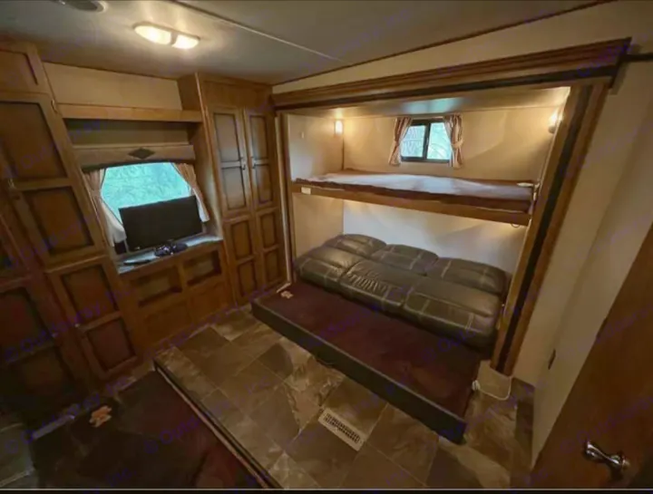 RV rental interior: A cozy living space with wood cabinets, TV, bunk beds, and a pull-out sofa.. Crossroads RV Rezerve 2016