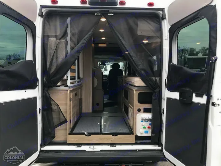 RV rental interior from the rear: open doors, mesh screen, compact kitchen/storage, and bed area visible.. Winnebago Solis 2023
