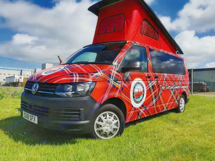 A vibrant red tartan VW pop-top campervan, branded "The Tartan Camper Company" for RV rental, parked on grass.. Volkswagen T6 Transporter LWB 2018