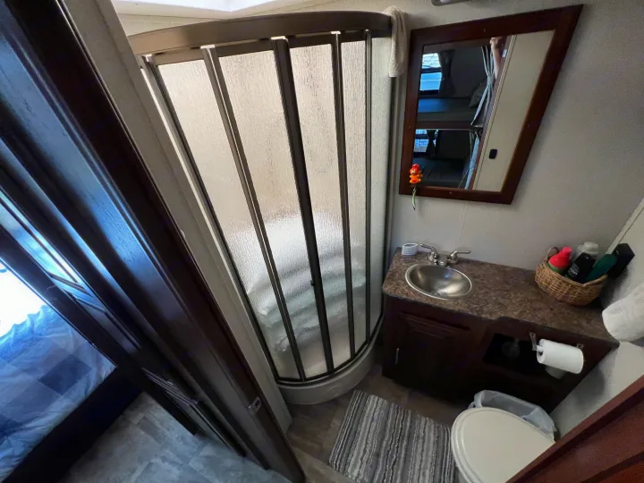 Inside an RV rental: a compact bathroom with a shower, sink, toilet, and mirror reflecting bunk beds.. Georgetown 351 DS Bunkhouse 2017