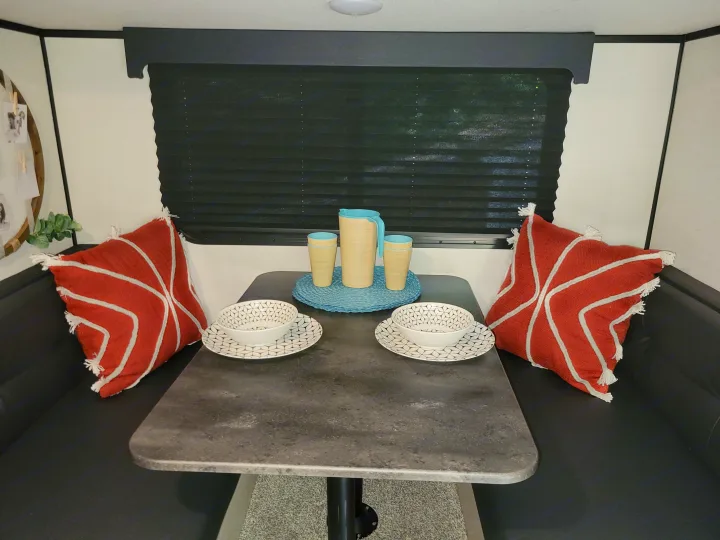 Cozy RV rental dining booth with table, place settings, and decorative pillows under a window blind.. Other Other 2022