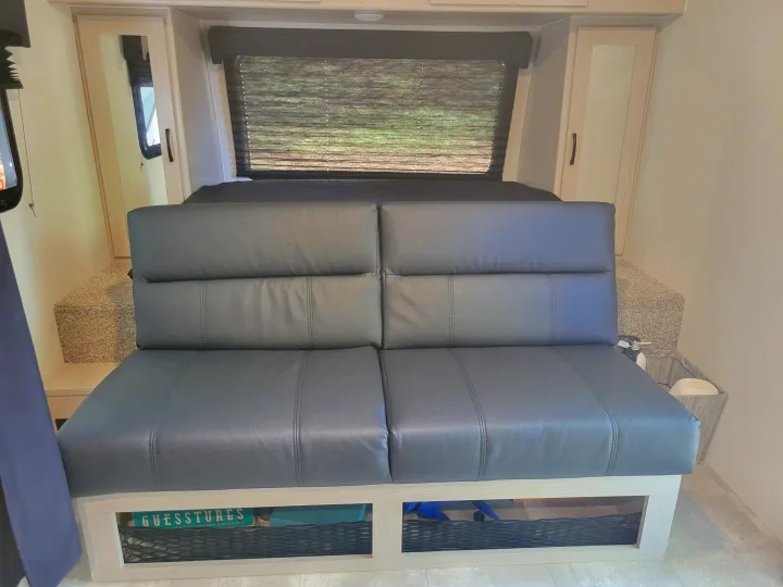 This RV rental features a grey convertible sofa, window with blinds, and smart integrated storage solutions.. Other Other 2022