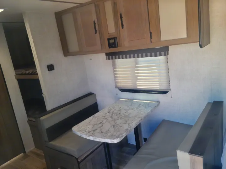 Clean RV rental interior: dinette with marble-look table, overhead cabinets, and bunk beds for travel.. Gulf Stream Ameri-Lite Super Lite 2021