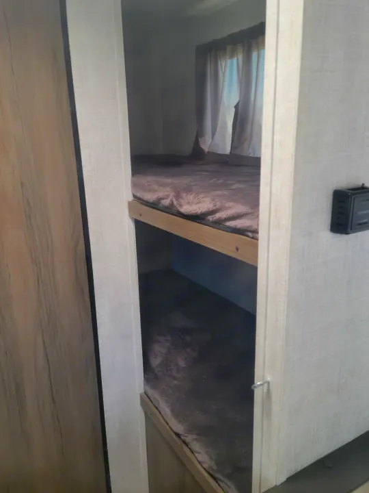Cozy RV rental bunk beds with plush mattresses, window curtains, and interior controls shown.. Gulf Stream Ameri-Lite Super Lite 2021