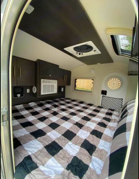 This RV rental's sleeping area features a large checkered bed, AC, overhead storage & vent.. NuCamp T@G MAX XL BOONDOCK 2021