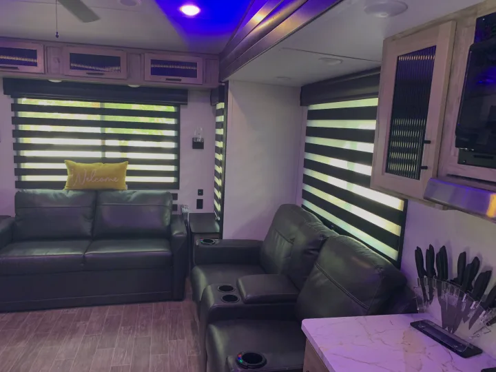 Modern rv rental interior with comfy sofas, zebra blinds, and blue accent lighting, perfect for a cozy living space.. Forest River Cherokee Arctic Wolf 2022