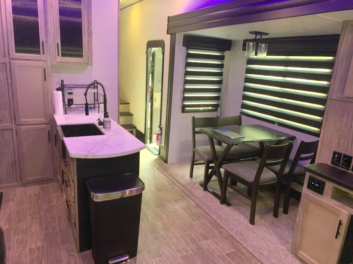 Modern RV rental interior features a sleek kitchen with a sink, a dining area with a table and chairs, ideal for travel.. Forest River Cherokee Arctic Wolf 2022