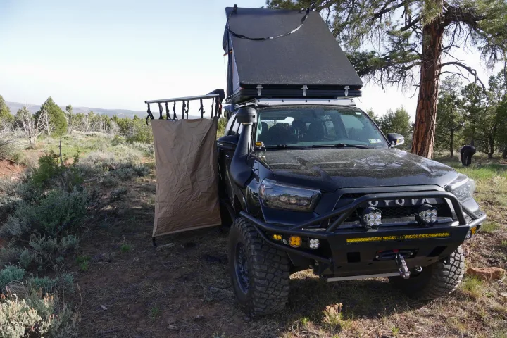 A rugged black overlanding truck with a rooftop tent and side privacy shelter, perfect for your next rv rental style adventure.. Toyota 4Runner 2013