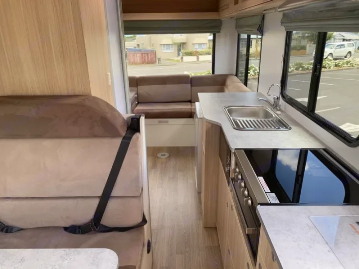 Clean RV rental interior featuring a compact kitchen with sink and stovetop, and comfortable U-shaped dinette seating.. Mercedes-Benz Sprinter 2022