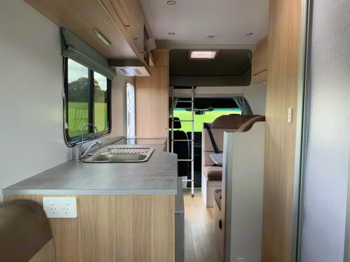 Inside an RV rental: a well-equipped kitchen, cozy dining area, and over-cab bunk, perfect for your next journey.. Mercedes-Benz Sprinter 2022