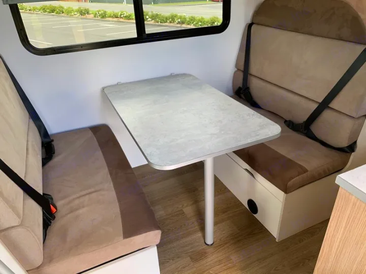 RV rental interior: cozy dinette with two cushioned seats, seatbelts, and a table, ideal for travel.. Mercedes-Benz Sprinter 2022