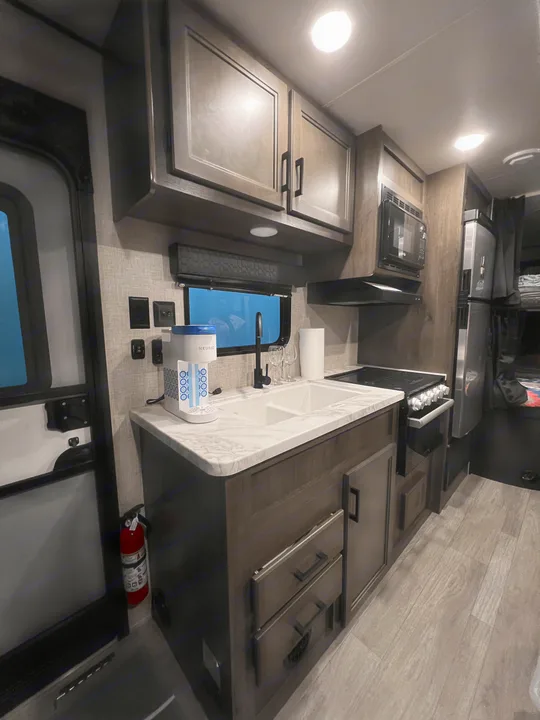 Spacious RV rental kitchen features stylish dark cabinets, essential appliances like a microwave & fridge, and cozy bunk beds.. Jayco Jay Flight SLX 8 2022