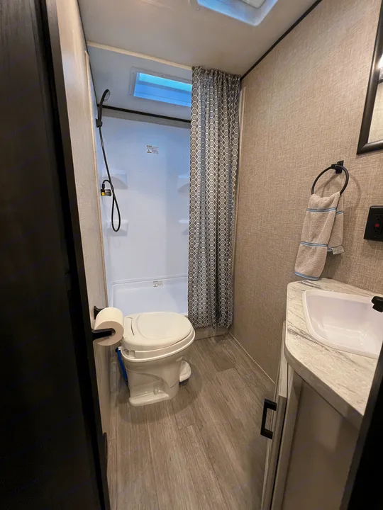 RV rental bathroom: Features a compact toilet, stand-up shower with curtain, and sink vanity. Functional & clean.. Jayco Jay Flight SLX 8 2022