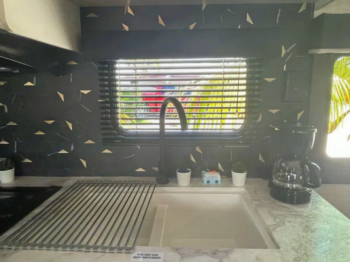 Modern RV rental kitchen with black backsplash, sink, coffee maker, and window view.. Jayco JAYCO JAY FLIGHT SLX 264BH 2022