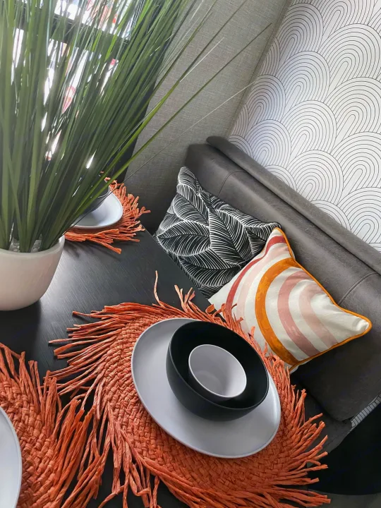 Modern RV rental dining area features a dark table, vibrant coral placemats, and stylish pillows, creating a cozy and inviting space.. Jayco JAYCO JAY FLIGHT SLX 264BH 2022