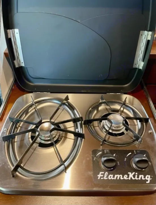 Compact FlameKing two-burner stove in an RV rental, ideal for mobile cooking with a practical hinged cover.. Driftwood Trailers Other 2022