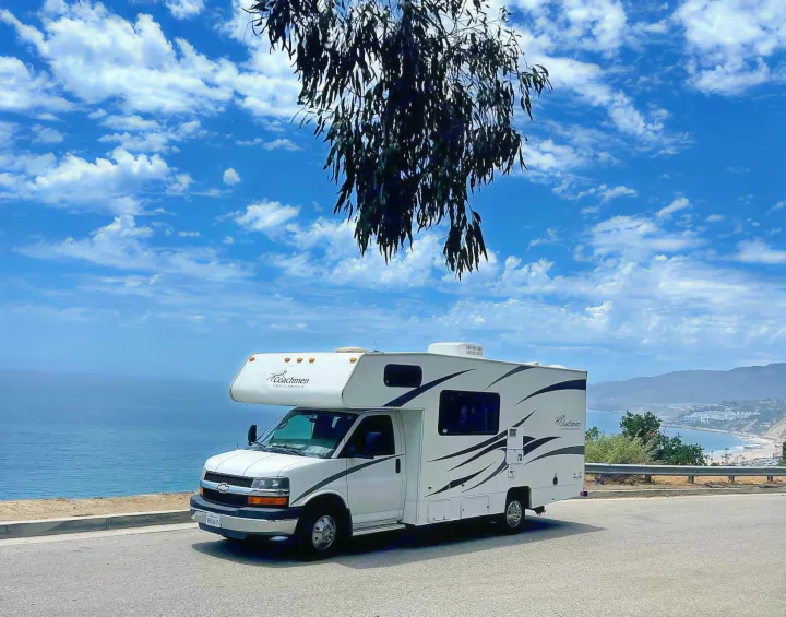 White Coachmen Freelander **RV rental** parked at a scenic ocean overlook, with a vast blue sky and distant coastline.. Forest River Coachmen Freelander 2010