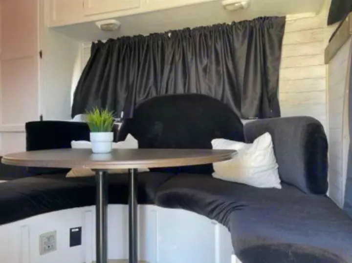 This RV rental features a comfortable dinette: black U-shaped seating, round table, and privacy curtains.. Forest River Coachmen Freelander 2010