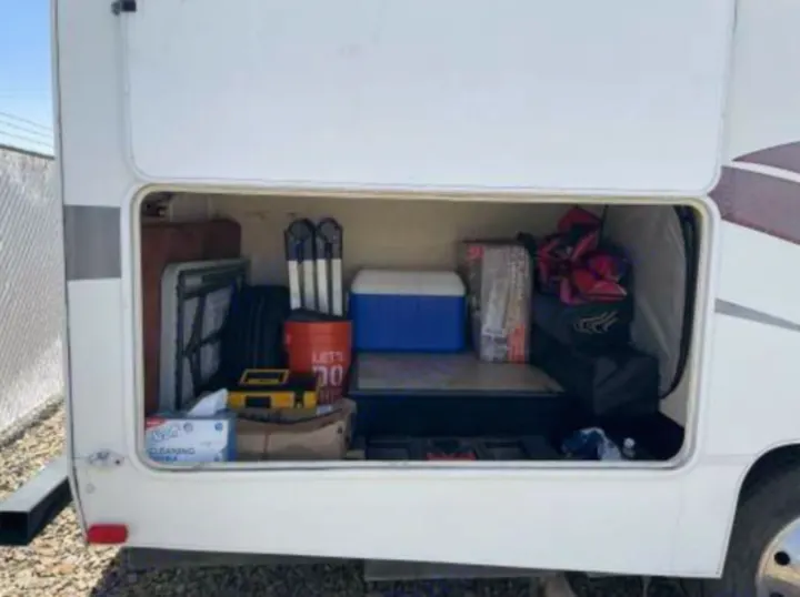 Explore an RV rental's accessible exterior storage, packed with a cooler, folding table, and camping gear.. Forest River Coachmen Freelander 2010