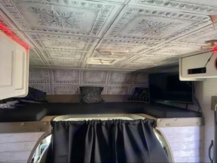 RV rental's custom interior features a decorative ceiling, elevated bunk bed, TV, and black privacy curtains.. Forest River Coachmen Freelander 2010