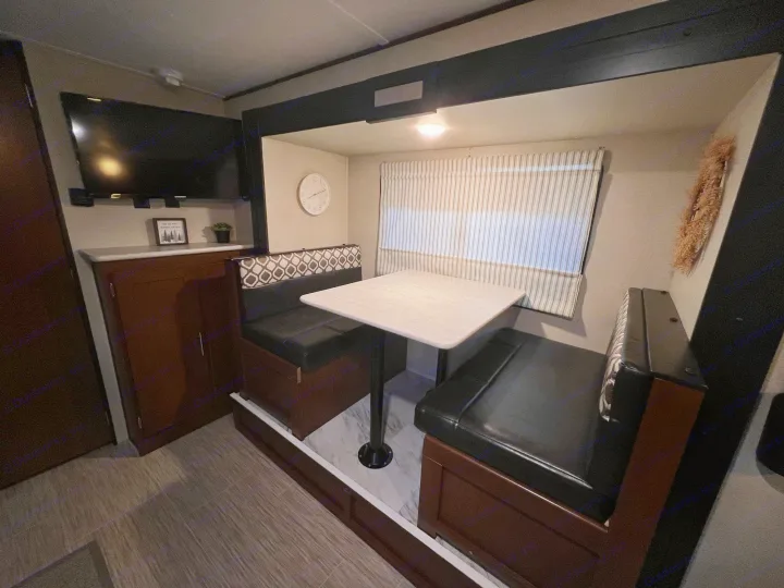 RV rental: Dinette with table, benches, and TV mounted on wall. Brightly lit interior for dining/relaxation.. PTX Forest River PDX170 2019