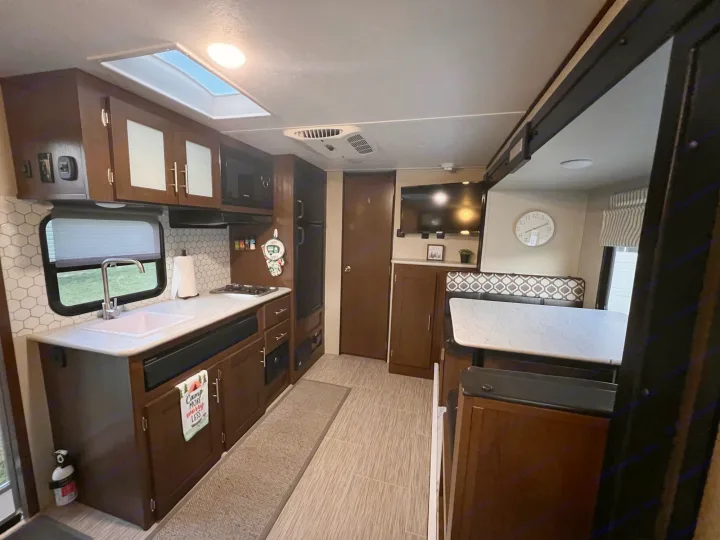 Well-appointed RV rental interior: kitchen with microwave, sink, and cabinets, plus a dinette and TV. Ready for your next trip.. PTX Forest River PDX170 2019