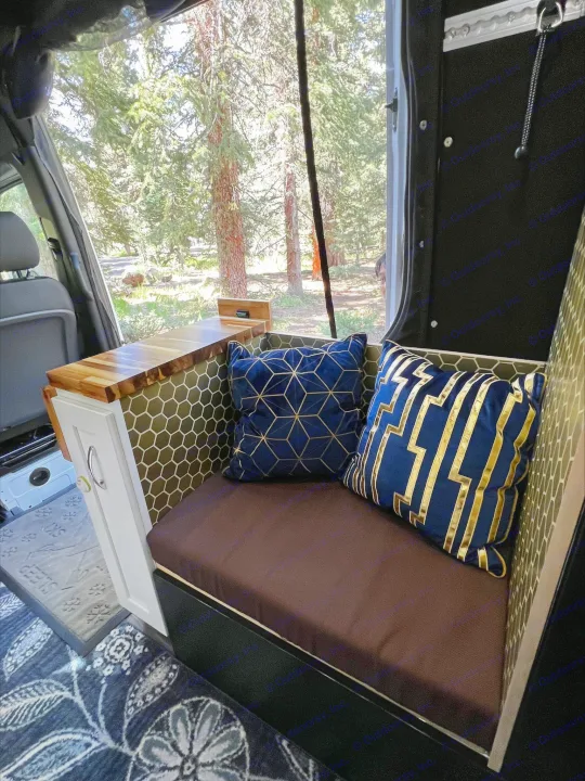 Stylish camper van rv rental interior with custom seating, accent pillows, and a peaceful forest view.. Mercedes-Benz Sprinter 2021