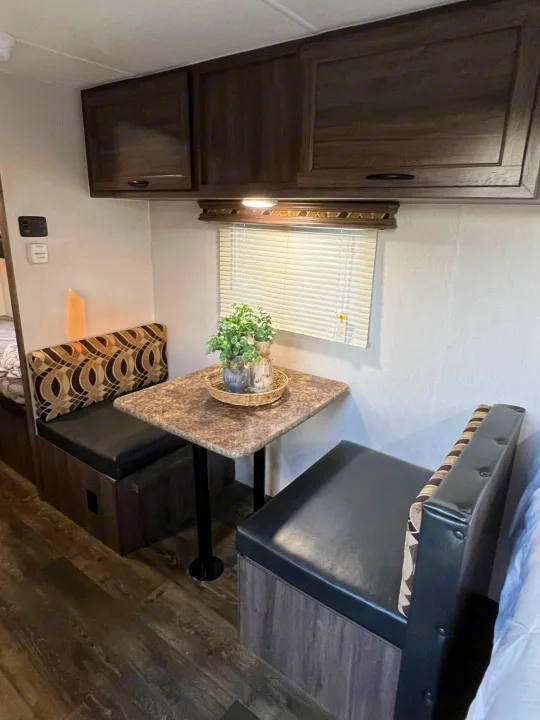 RV rental interior: cozy dinette with dark seating, patterned backrests, a table, and overhead cabinets. Ready for your trip.. Pacific Coachworks Pacifica XL 2020