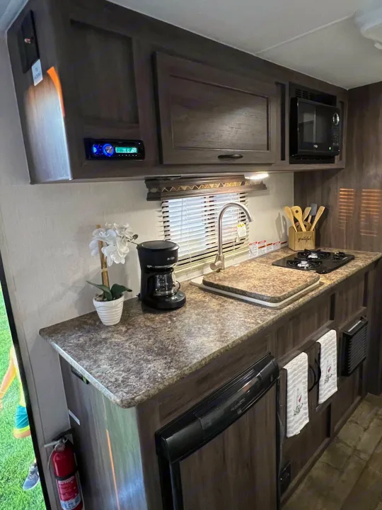 Explore this RV rental galley: compact kitchen with sink, stove, microwave, fridge, coffee maker, and stereo for comfy travels.. Pacific Coachworks Pacifica XL 2020