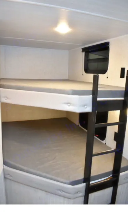 RV rental: Bunk beds with grey mattresses, a ladder, and window for extra sleeping space in a camper.. East to West Other 2022